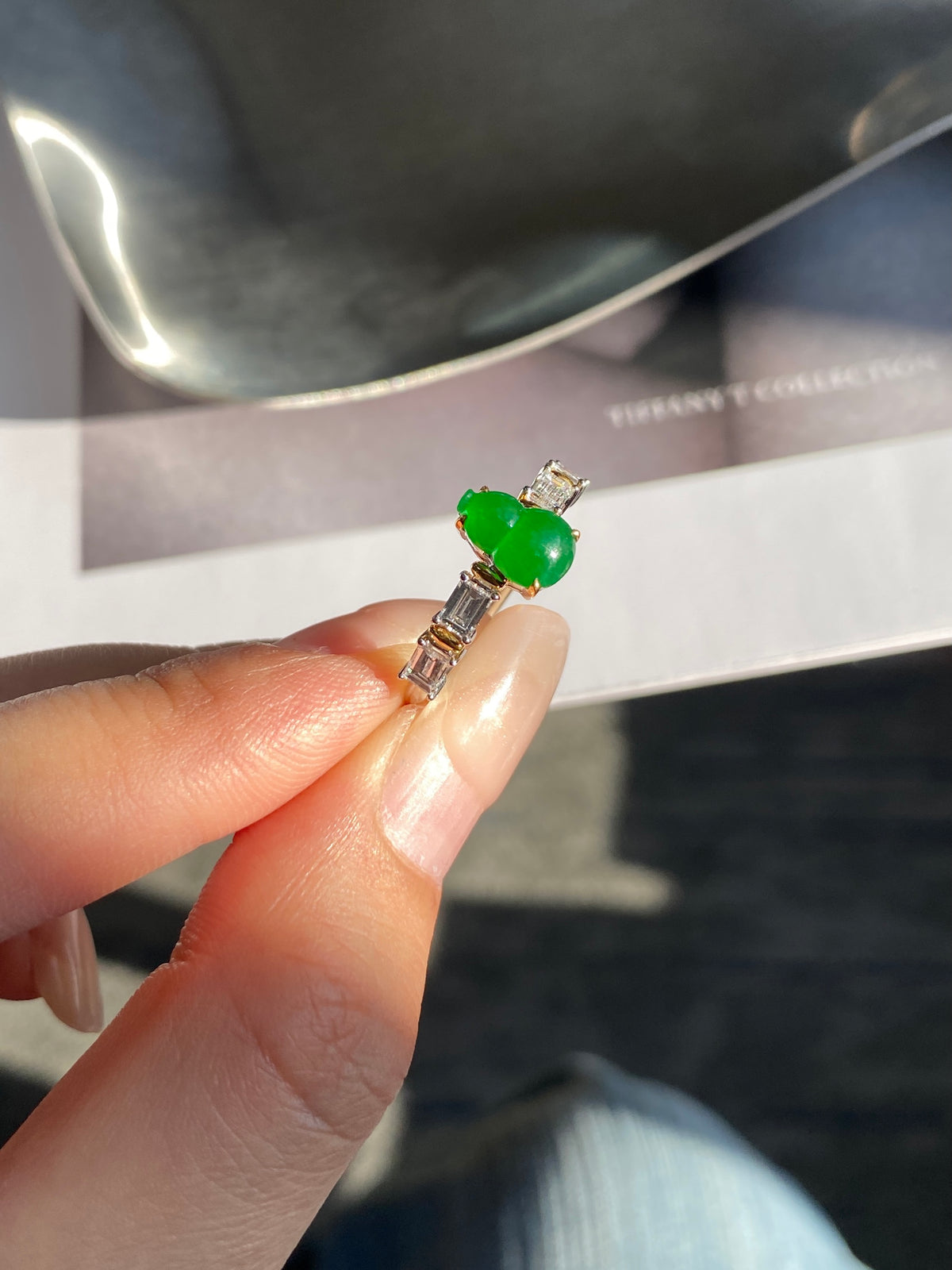 Green gemstone gourd ring on finger, gold-tone prongs and clear side stones