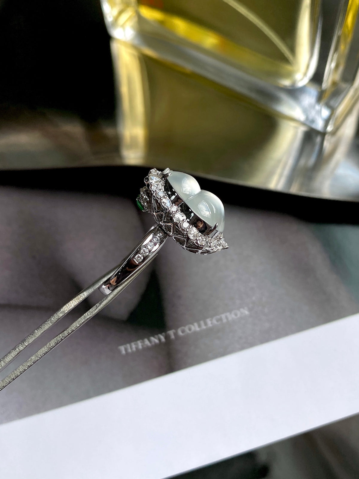 Silver-tone oval jade cabochon ring with double halo stones, angled view