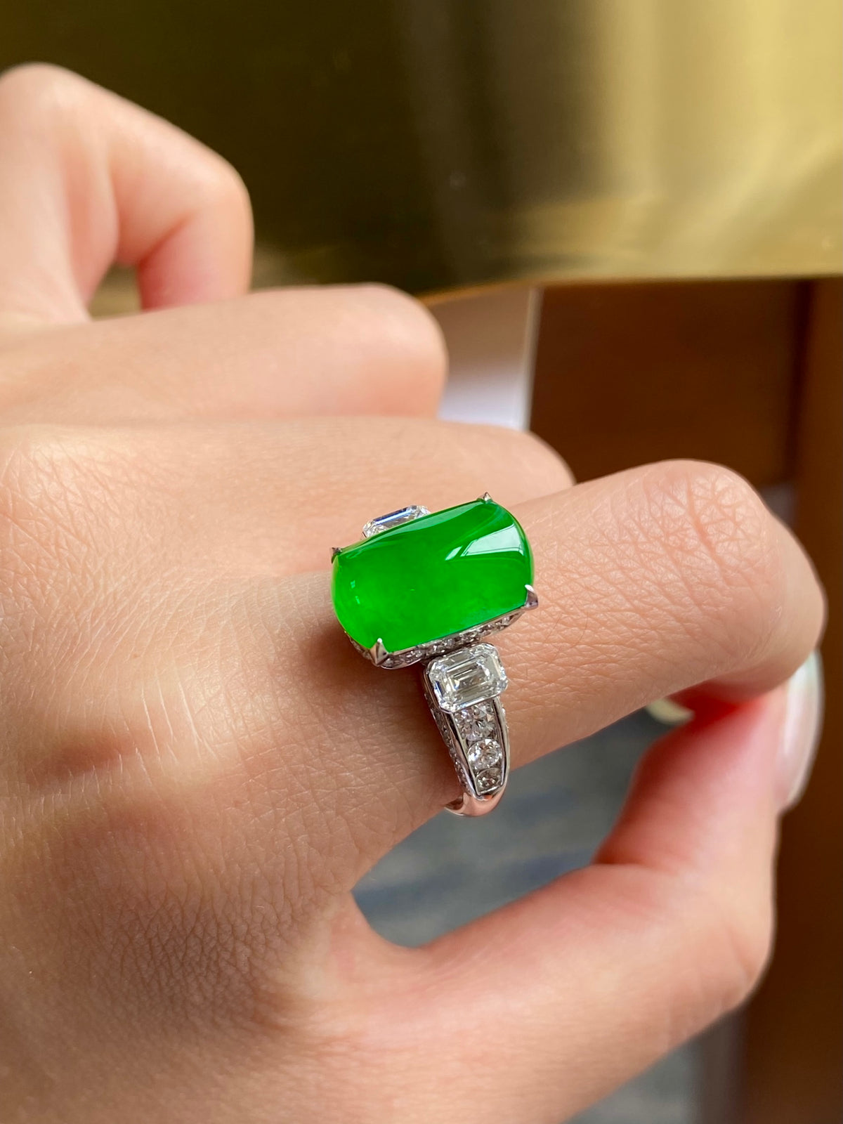 Green jadeite tablet ring on finger with sparkling baguette diamond details