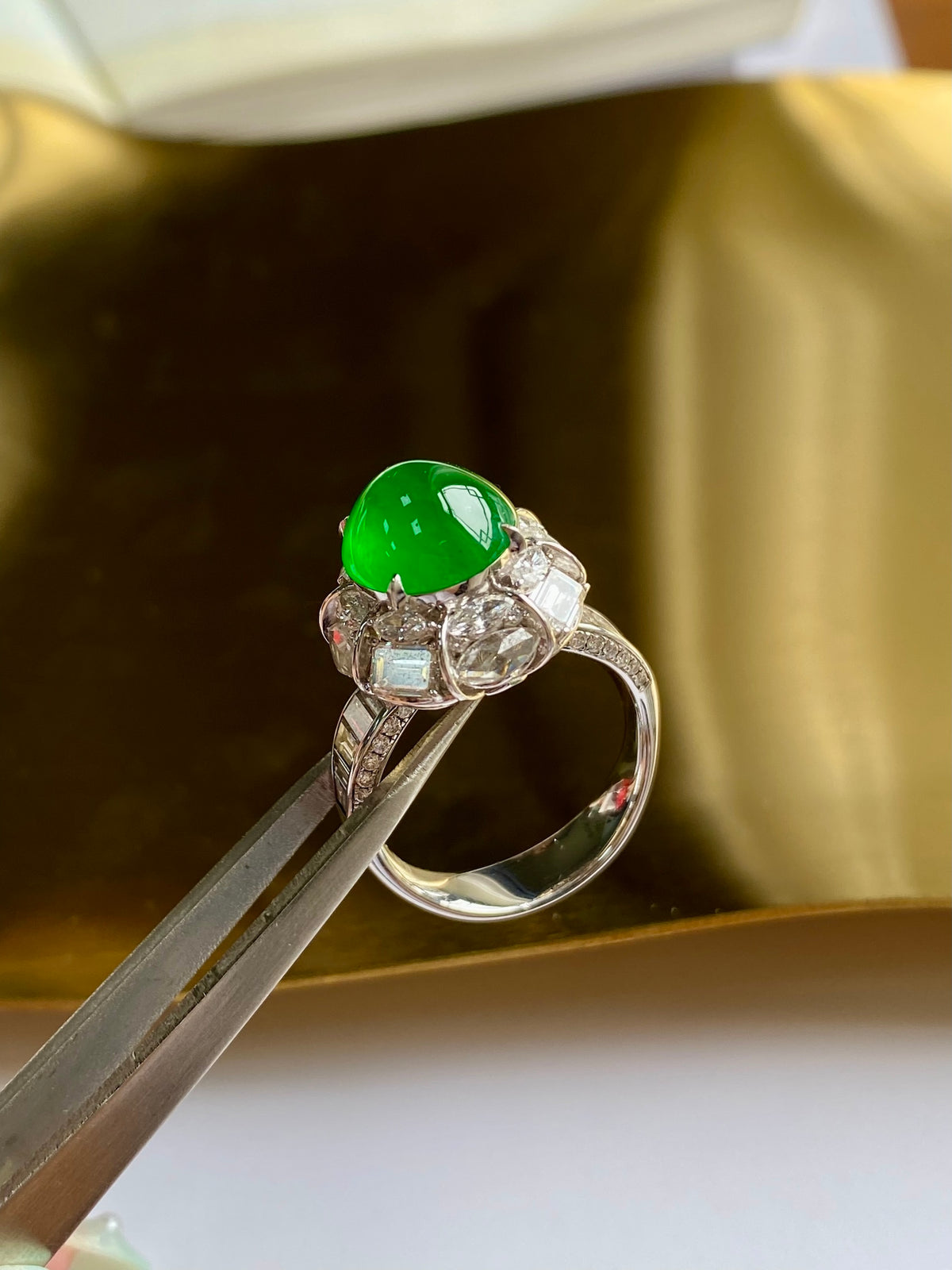 Green jade cabochon ring from side angle with prong-set clear stones