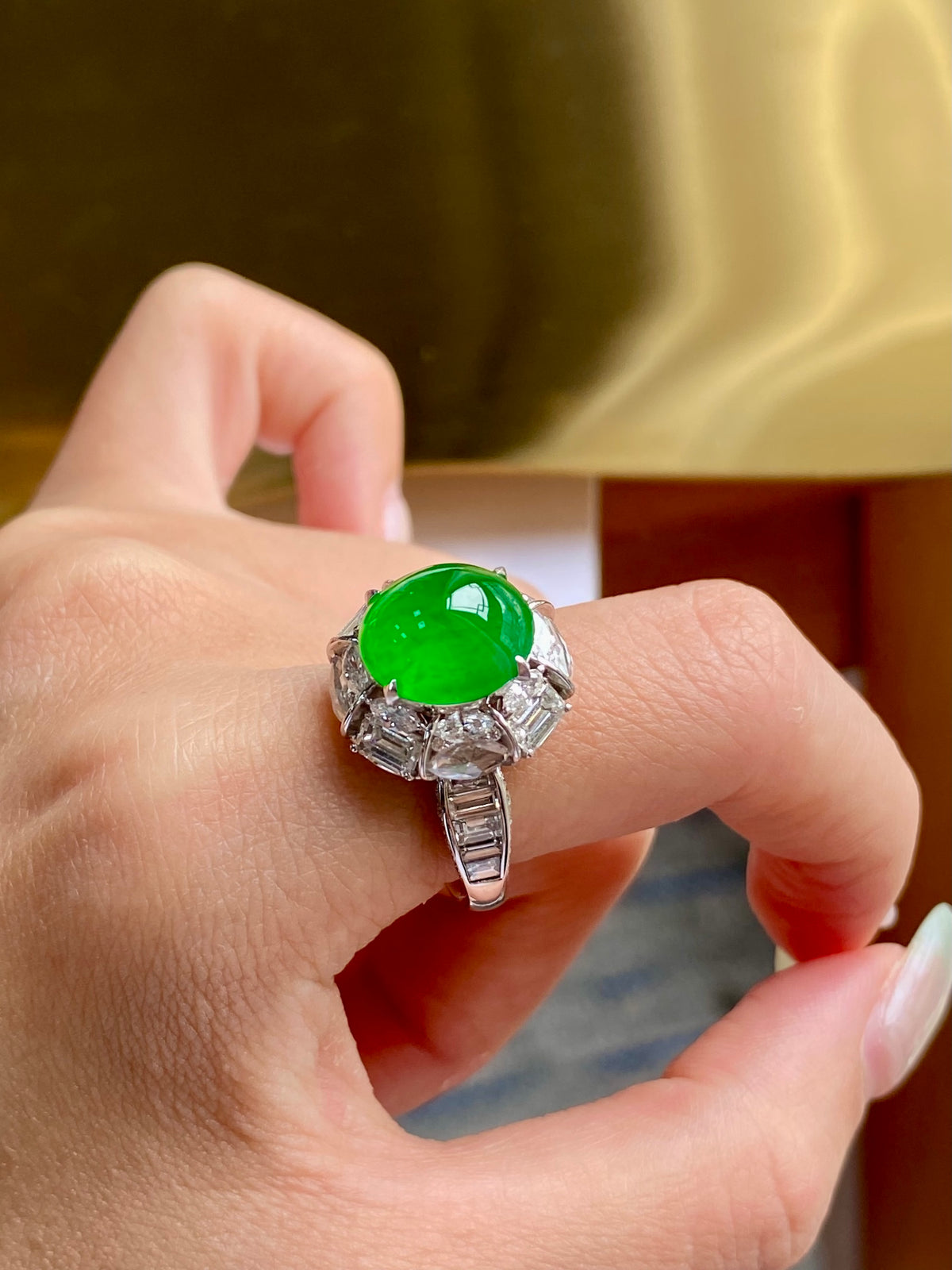 Green jade cabochon ring on finger with prong-set clear stone band