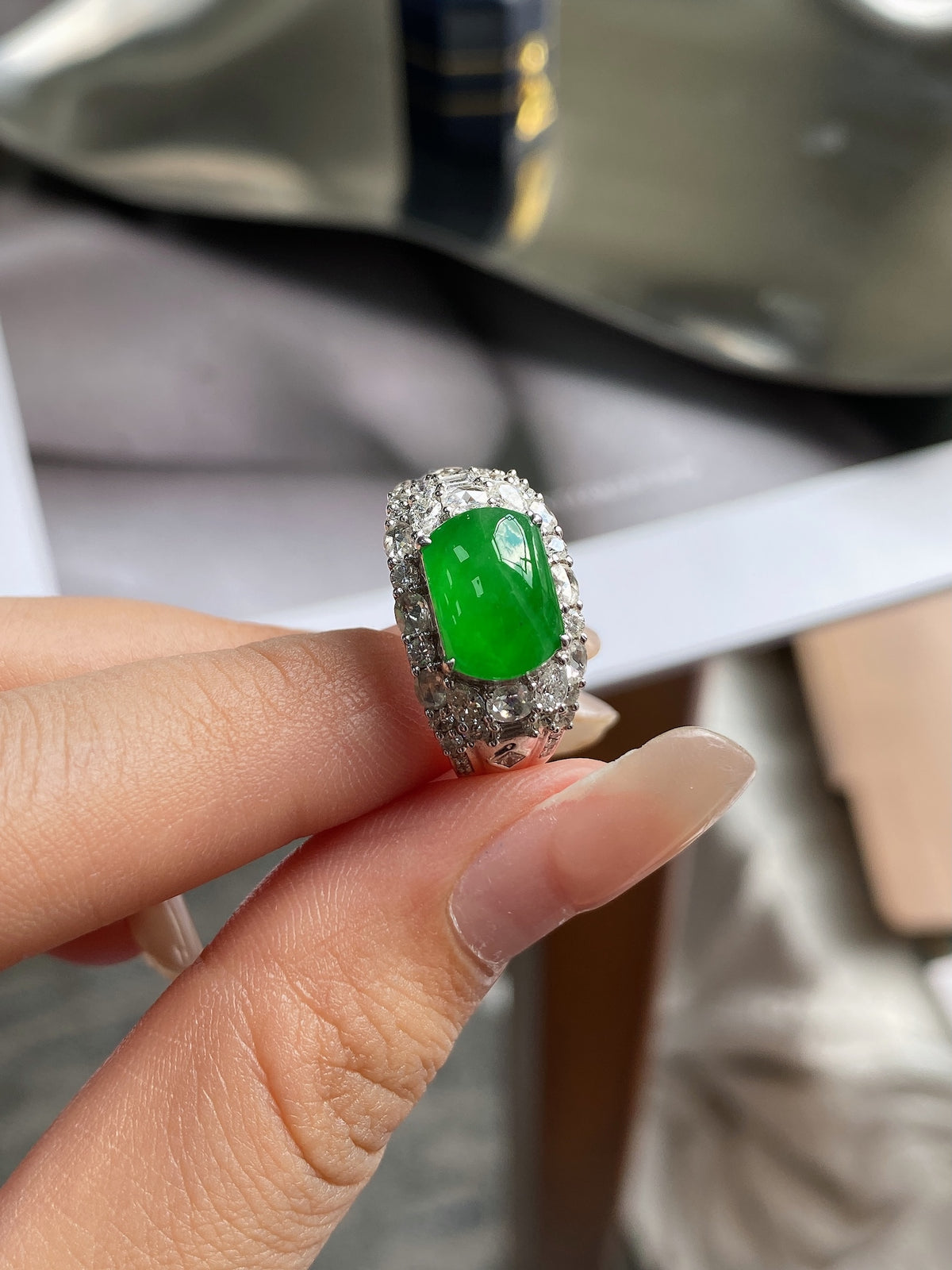 Green jadeite plaque ring with halo of pave stones, oval gemstone on silver band