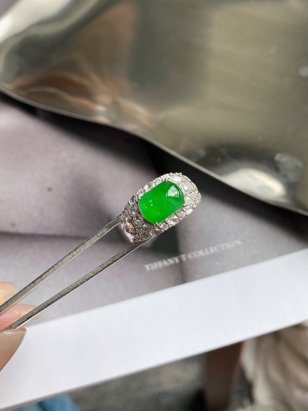 Green jadeite plaque ring with oval center stone and textured pave band, close-up