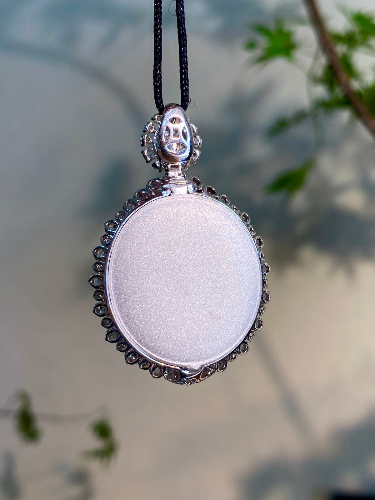 Silver-tone framed cabochon pendant on black cord, small top bail detail