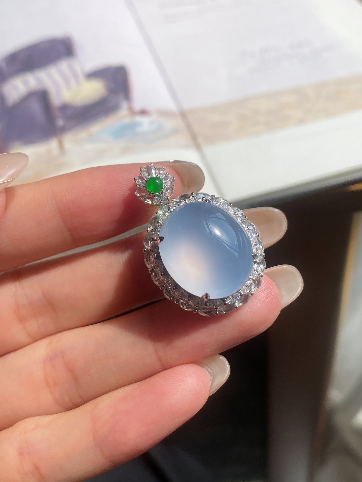 Light blue oval cabochon pendant with sparkling halo and small green top stone