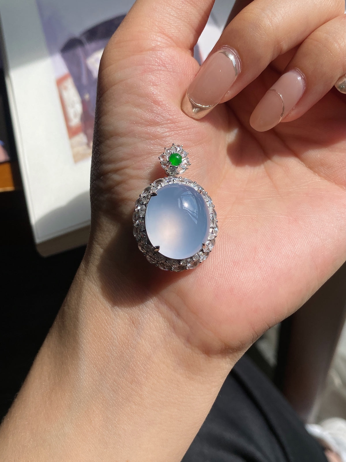 Light blue oval cabochon pendant with jeweled halo and small green top stone