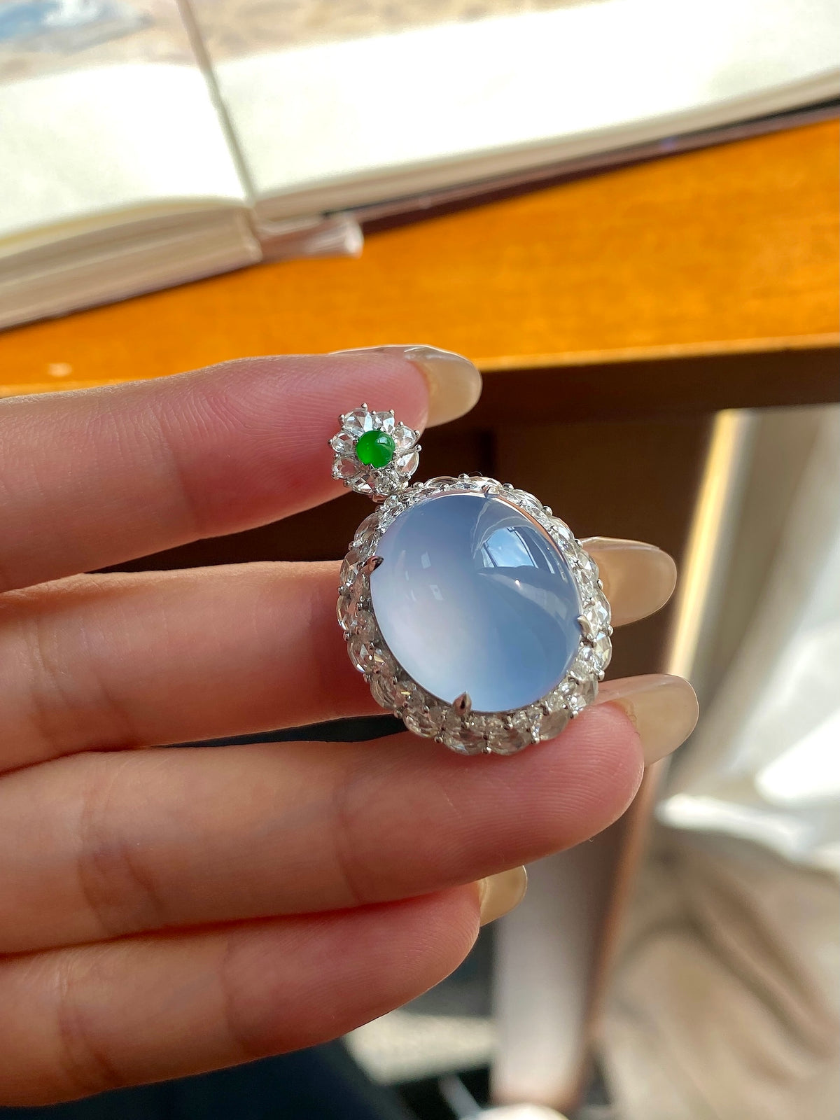 Light blue oval cabochon pendant with crystal halo and green gem top