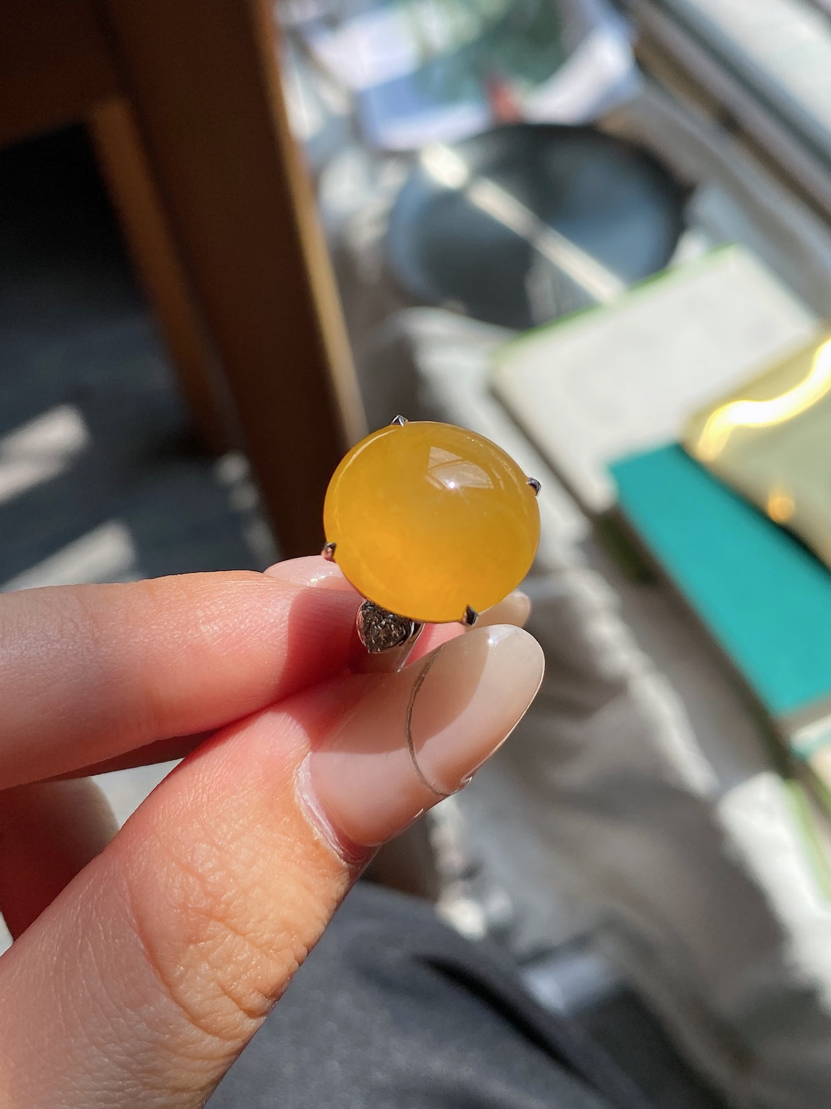 Golden yellow cabochon stone set on ring with dark metal halo