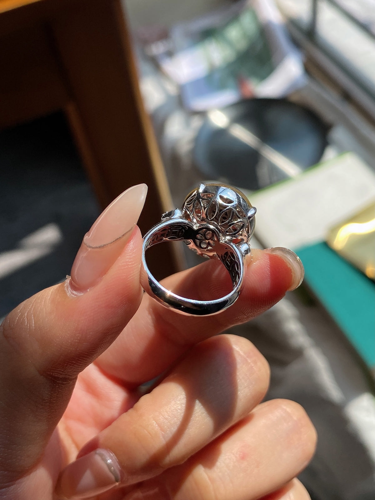 Jadeite cabochon ring side view with filigree shank and dark blue prong setting