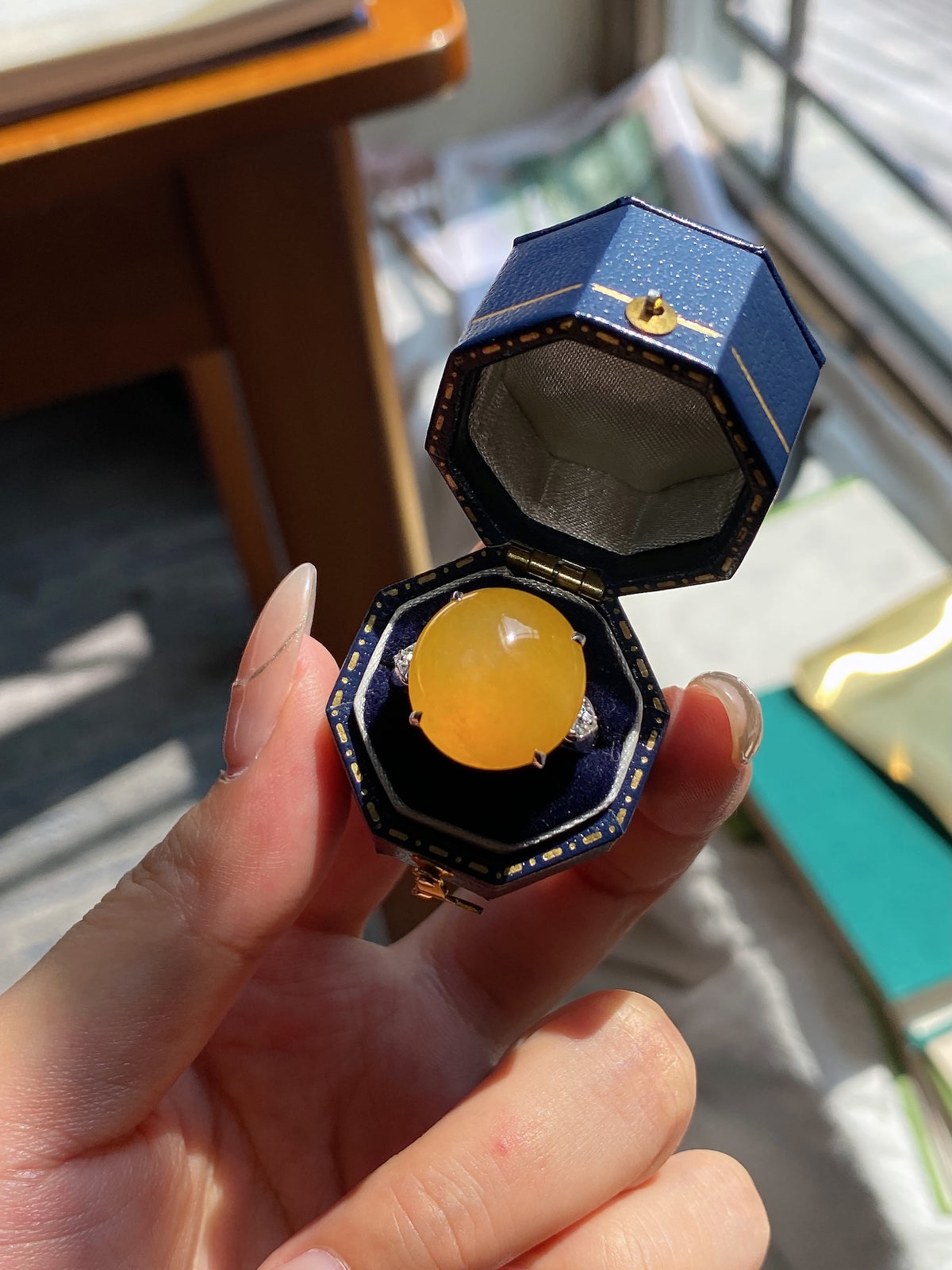 Jadeite cabochon ring with golden yellow oval stone in dark blue octagonal bezel