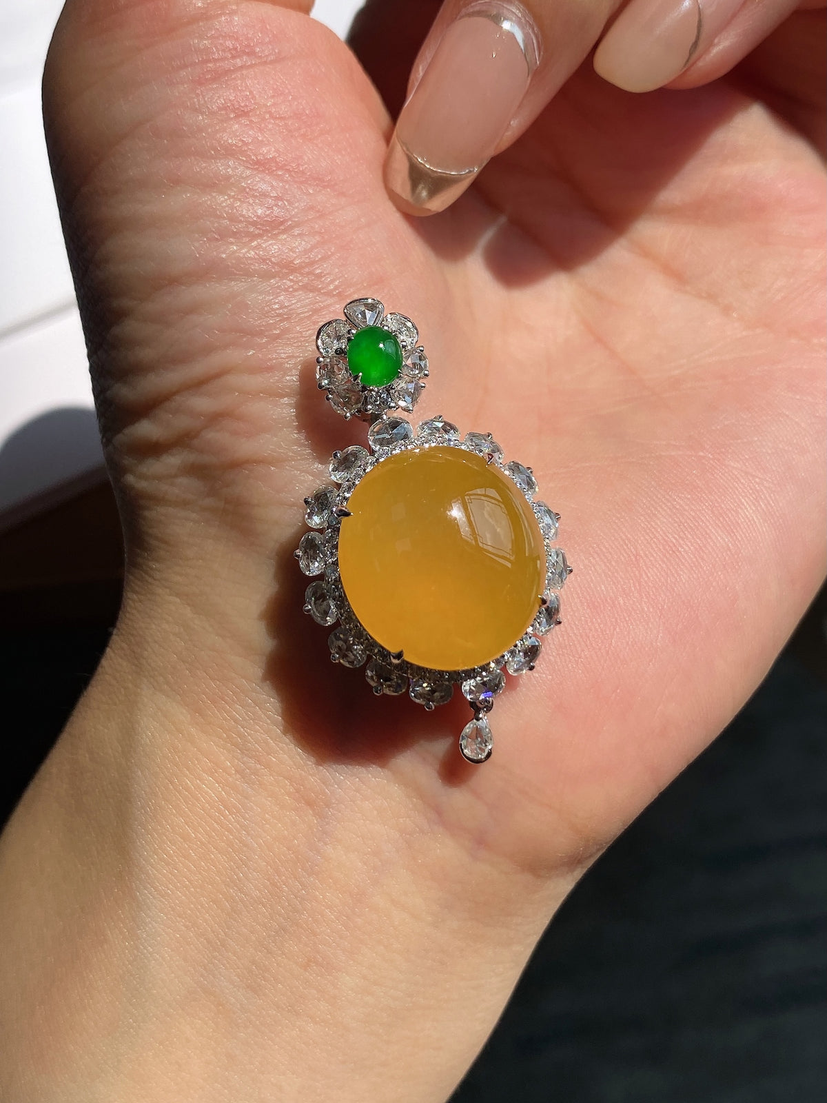Silver-toned pendant with round yellow cabochon and green flower accent