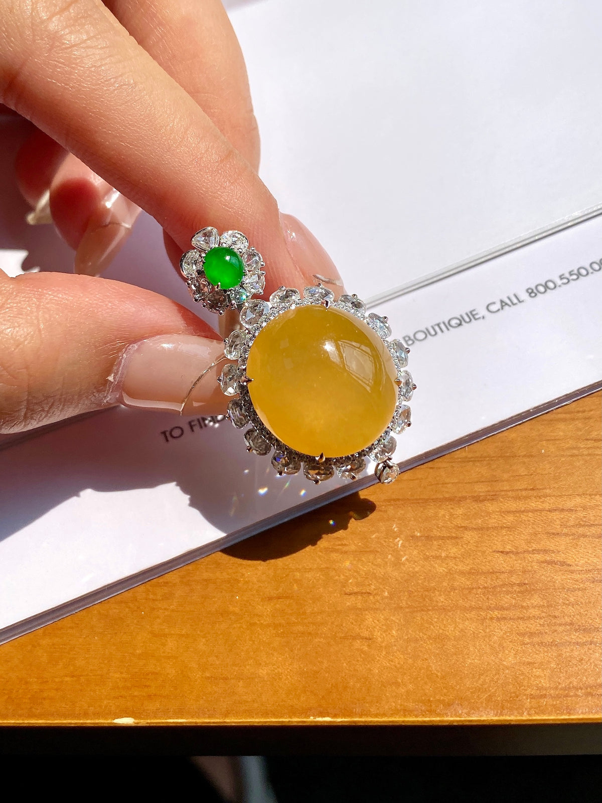 Silver-toned pendant with round yellow cabochon and green accent, shown on chain