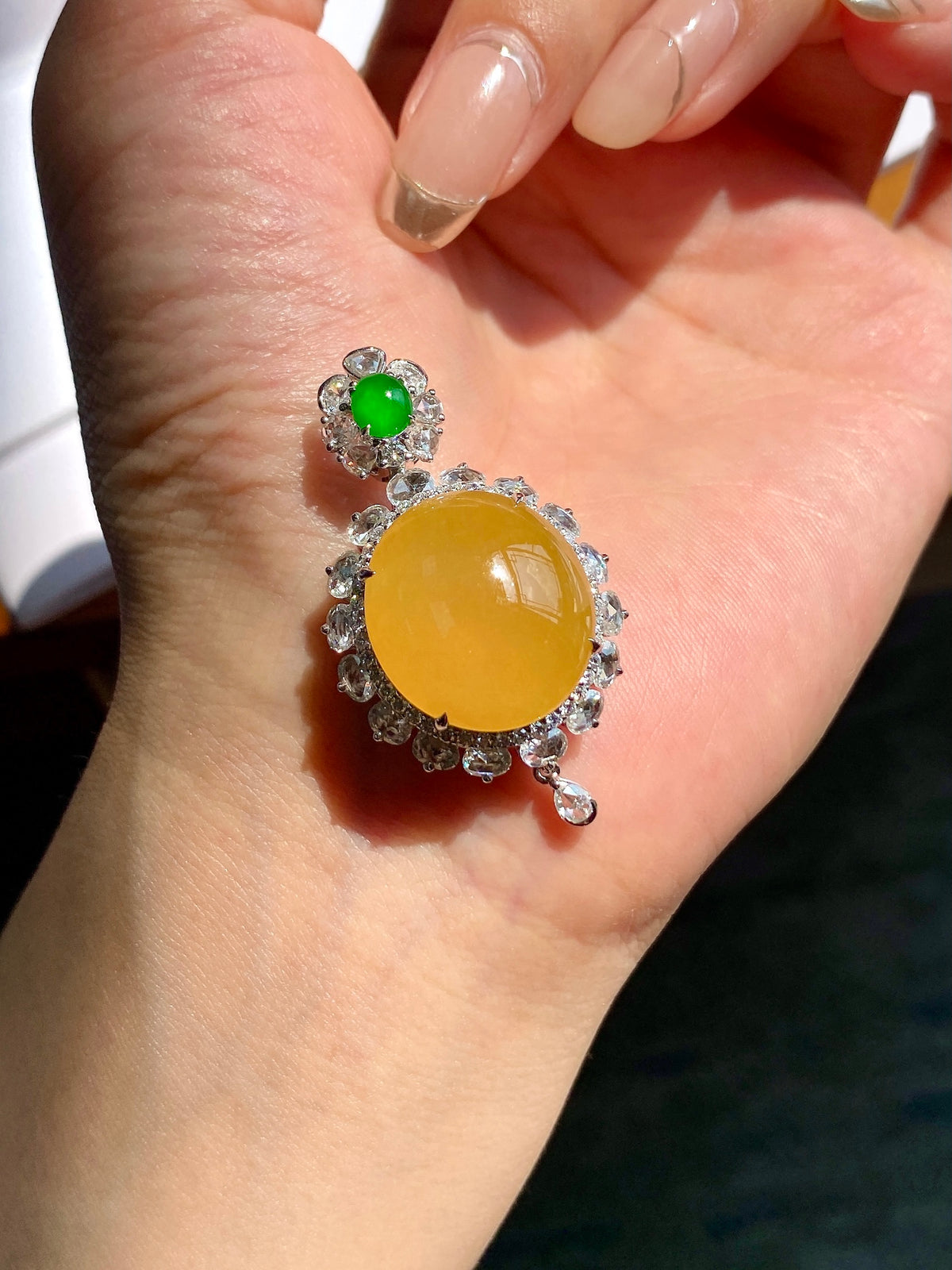 Silver-toned pendant with yellow cabochon center and green top stone, side view