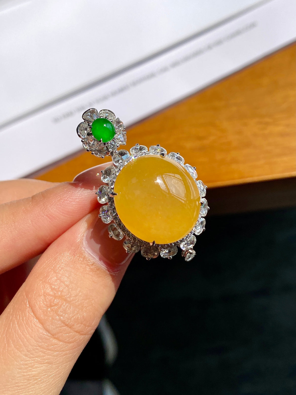 Silver-toned pendant close-up: round yellow cabochon with green top stone