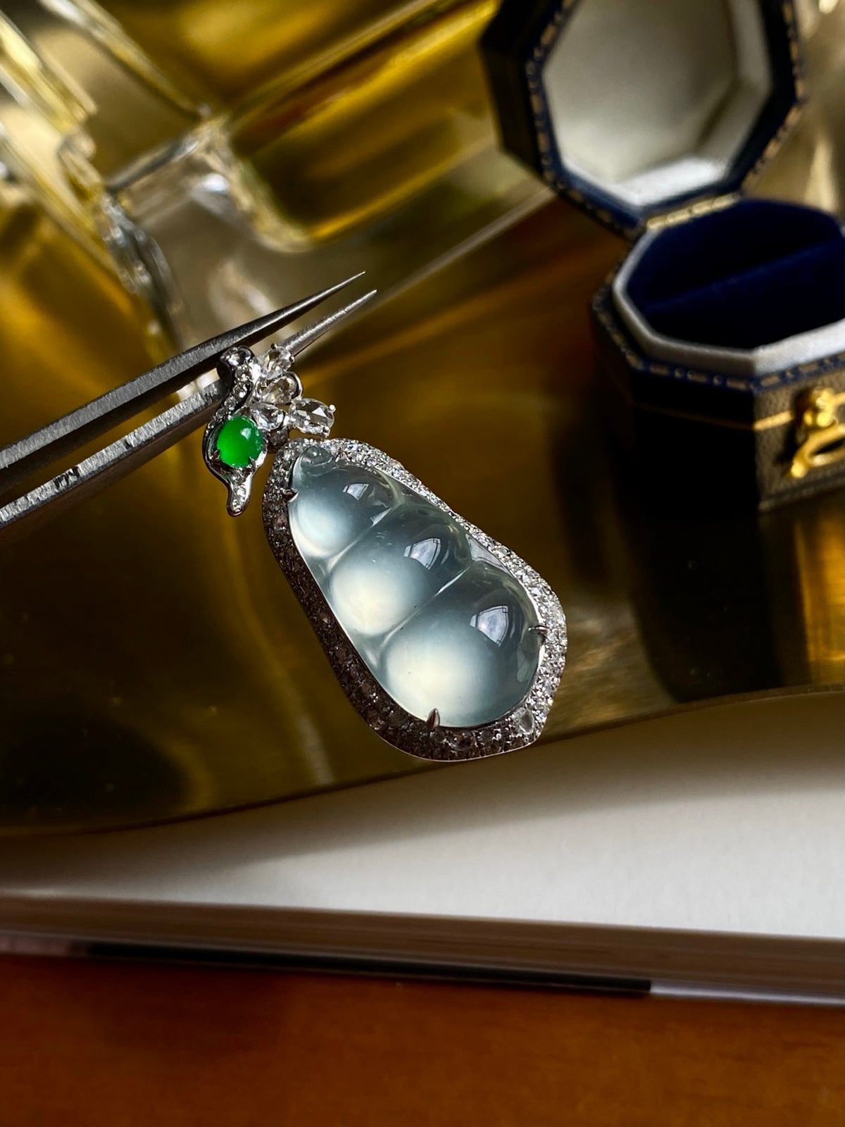 Teardrop jadeite bean pendant in silver setting with green gemstone detail
