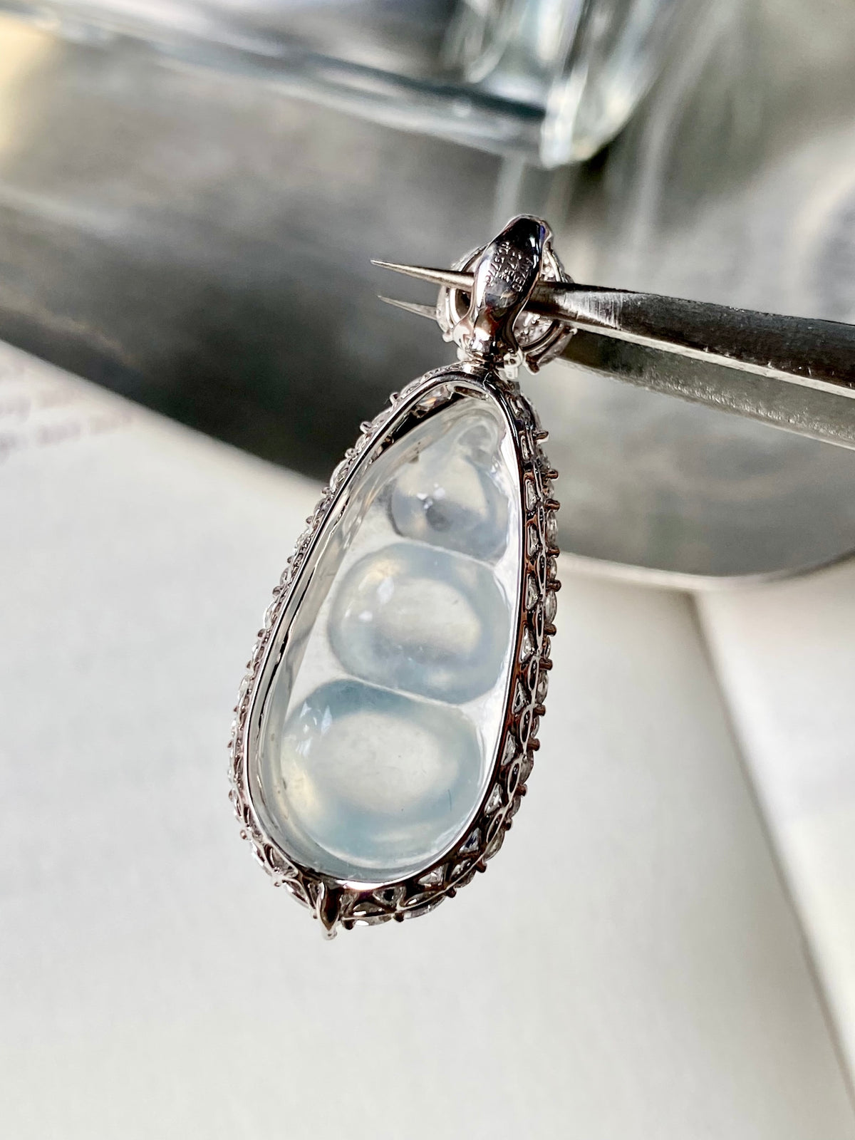 Ornate silver teardrop pendant with light-blue stone and small green cabochon top