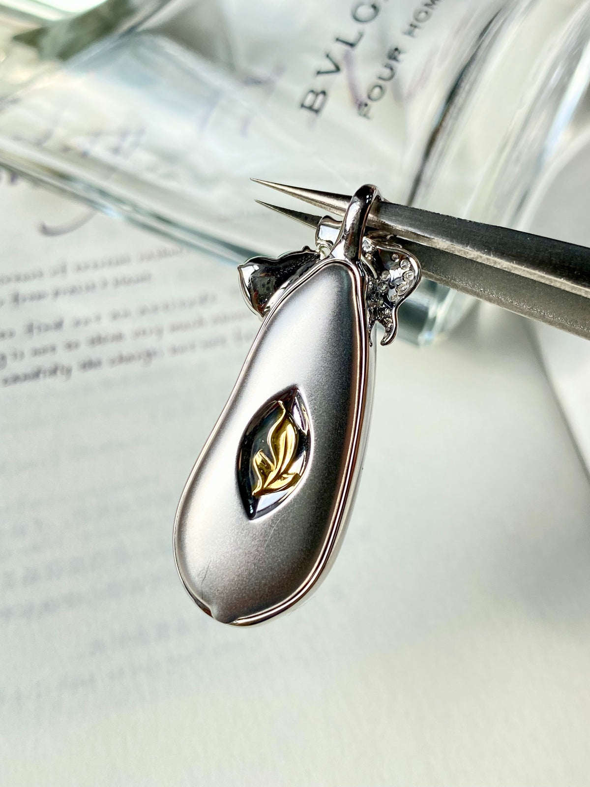Silver-tone jadeite bean pendant with dark inlay center, diamond-like top, no background
