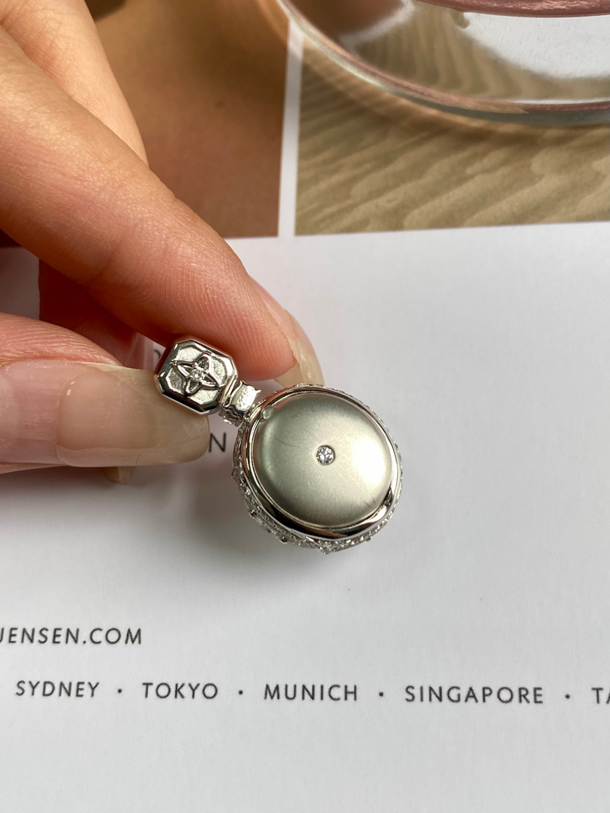Silver cabochon pendant with pale white oval stone and textured bezel setting