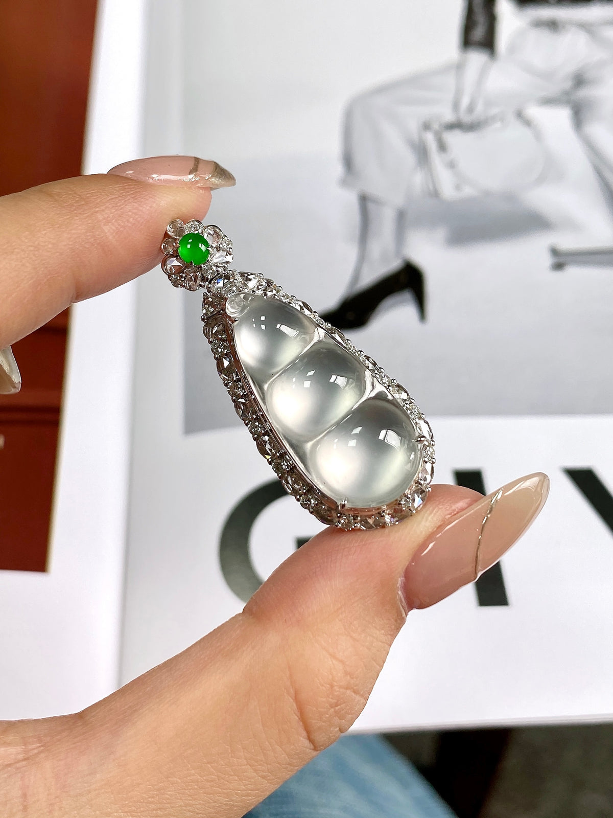 Silver rhinestone bean pendant with green round accent above three glossy white cabochons
