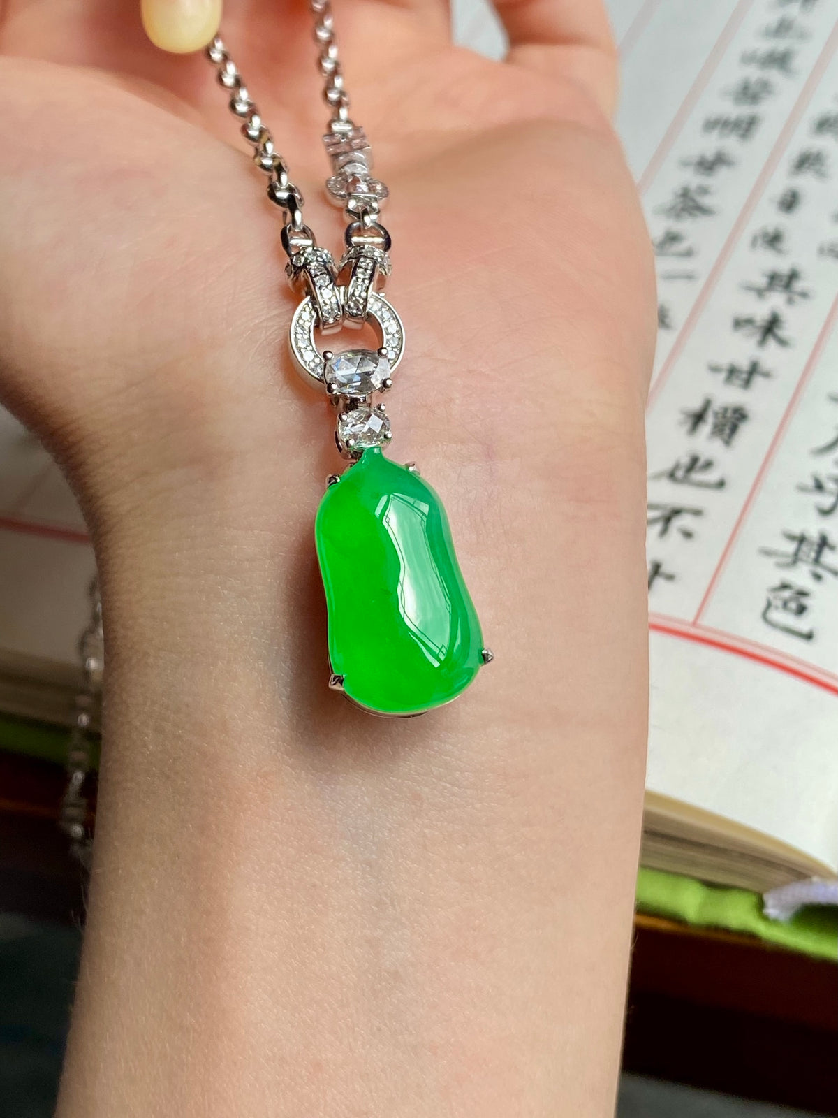 Green jadeite melon pendant necklace on hand with silver-toned rhinestone chain