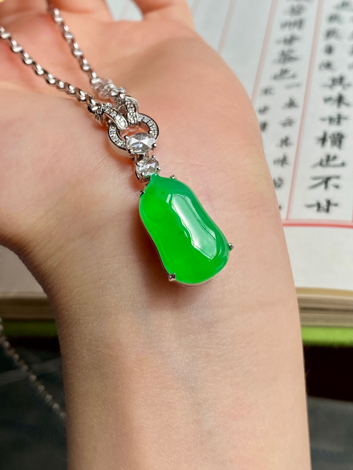 Green jadeite melon pendant necklace on hand with silver-toned setting and chain