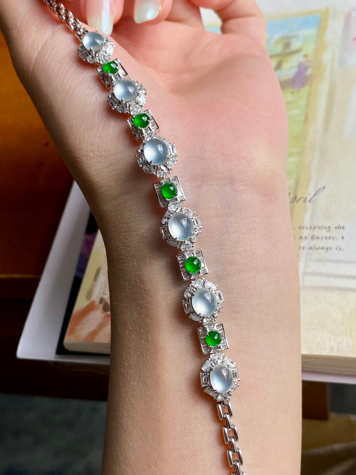 Jadeite cabochon bracelet on wrist, oval icy white stones with bright green accents