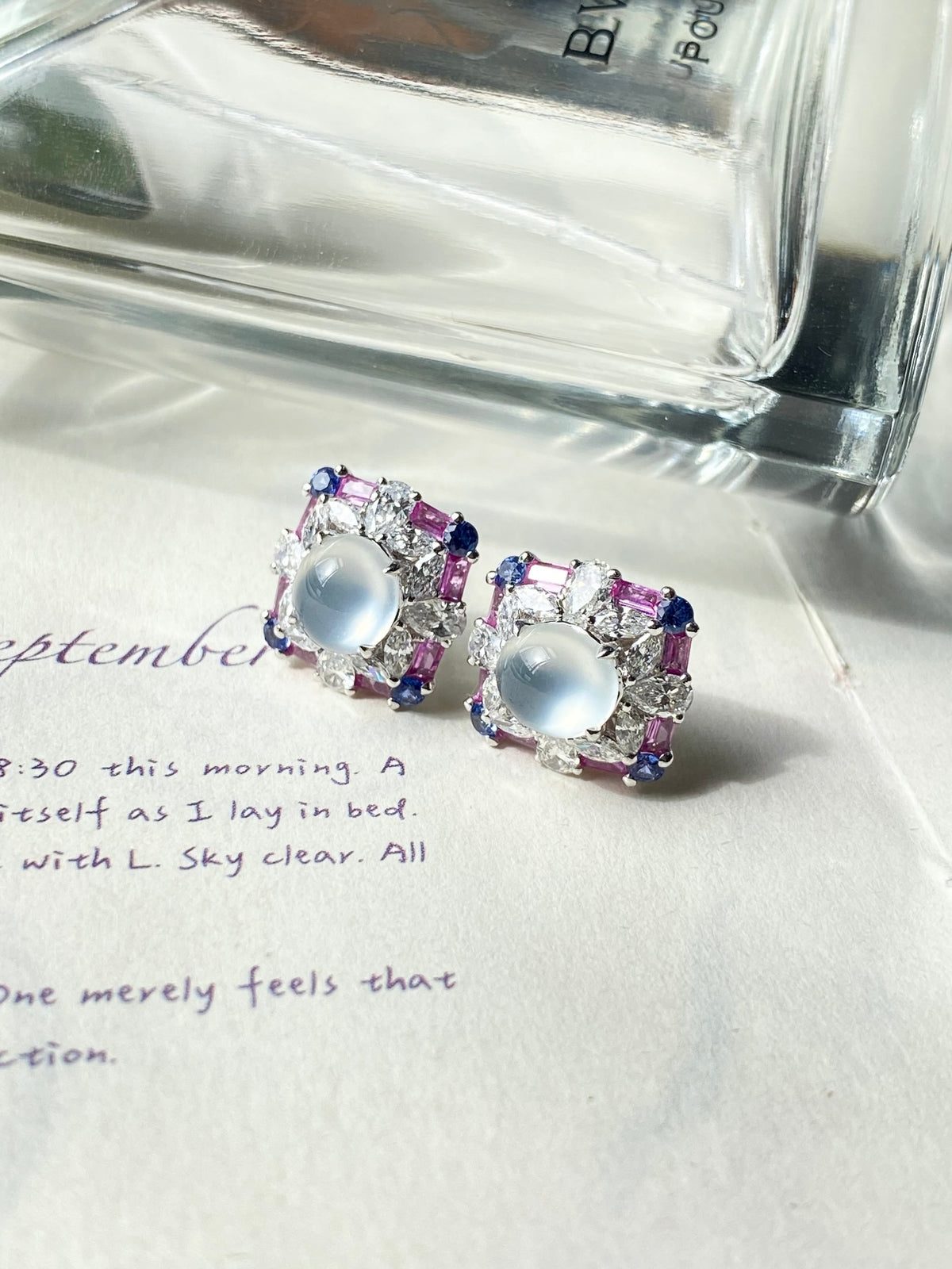 Pair of stud earrings with light blue oval cabochons and purple crystal square frames