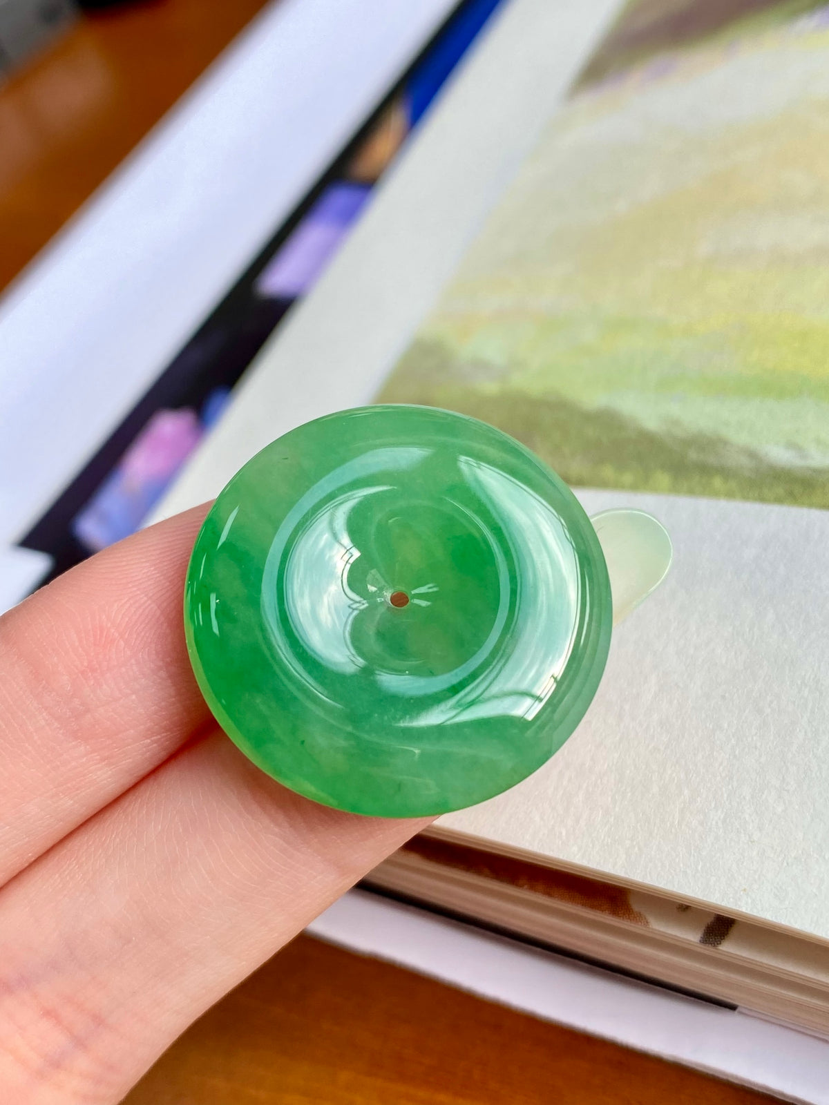 Green jadeite donut, unmounted round pendant with central hole; glossy translucent finish