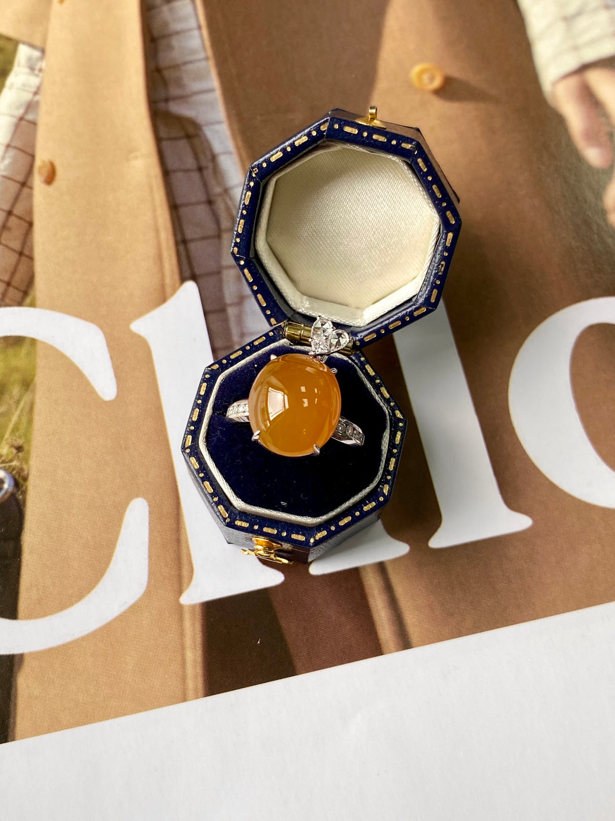 Amber cabochon ring pendant inside navy blue octagonal case with clear halo stones