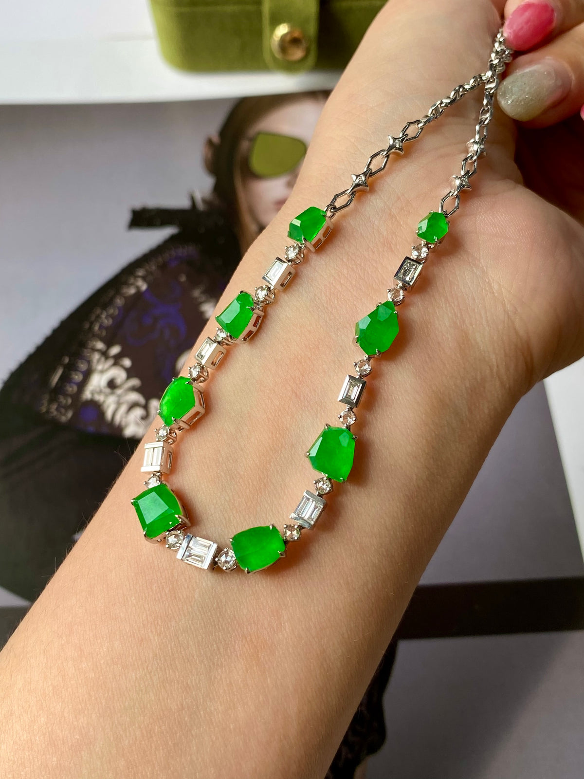 Green jadeite bead necklace on wrist with silver link chain and faceted green stones