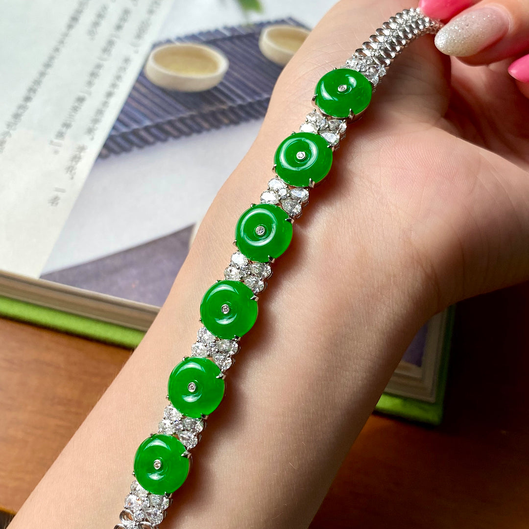 Green jadeite donut bracelet held in hand, with silver setting and clear stone links