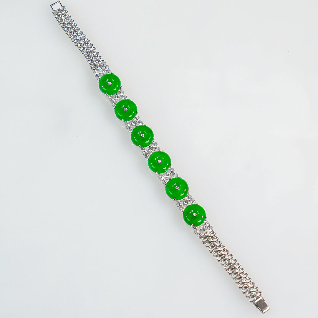Long silver bracelet with green jadeite donut beads and clear stone separators, angled view