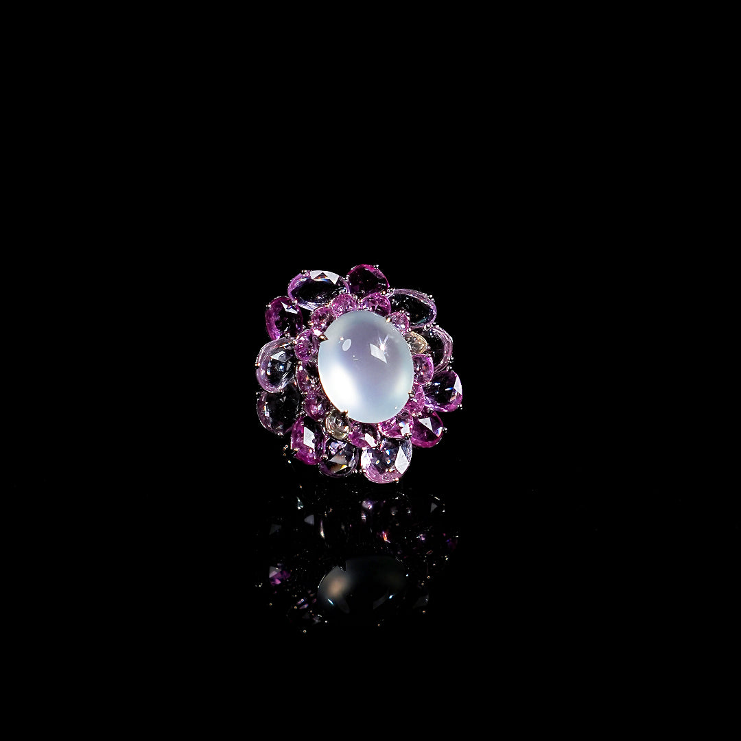 Floral gemstone ring with oval opalescent cabochon and purple gemstone halo in silver