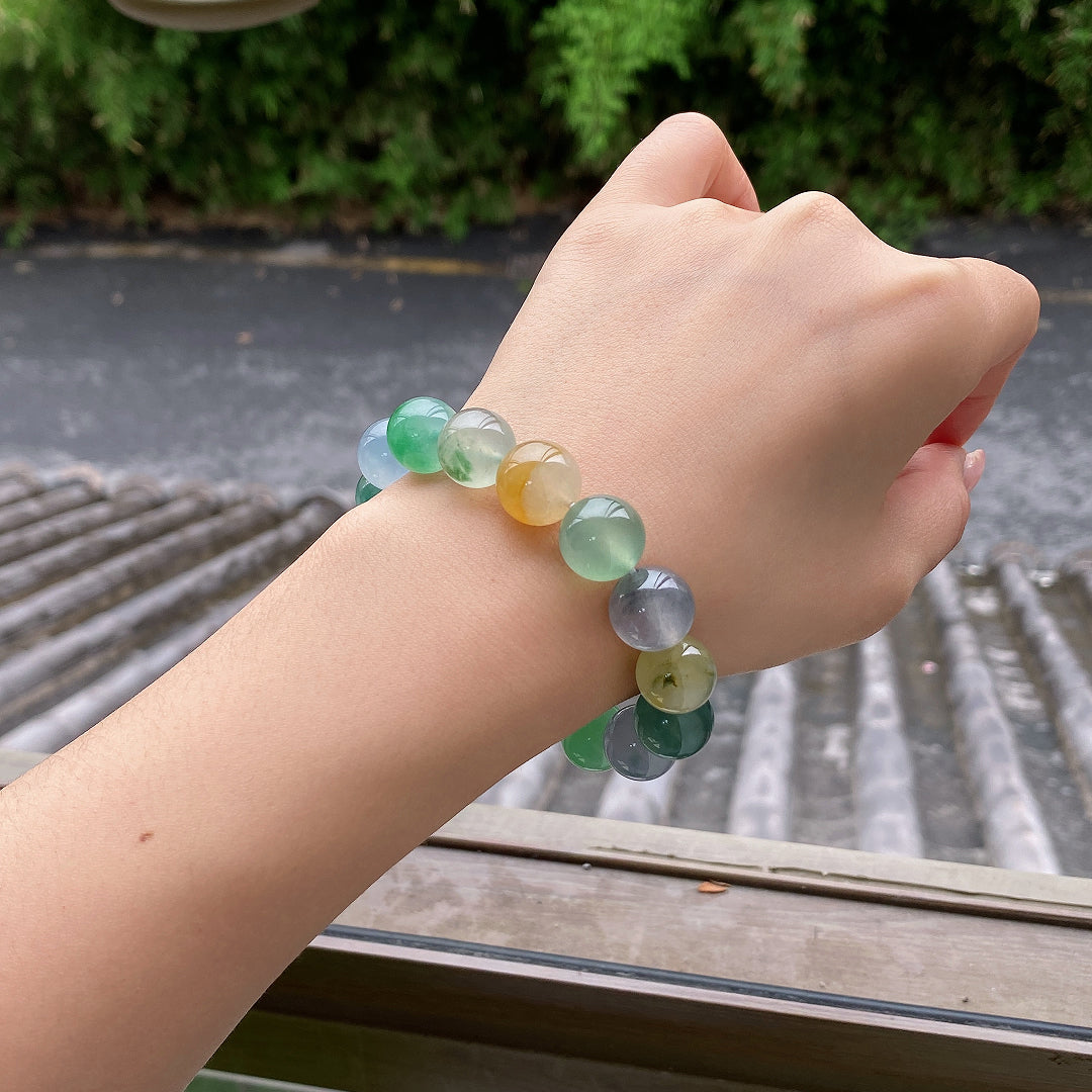 Multi-color jadeite beaded bracelet on wrist, green and lavender beads with a yellow bead