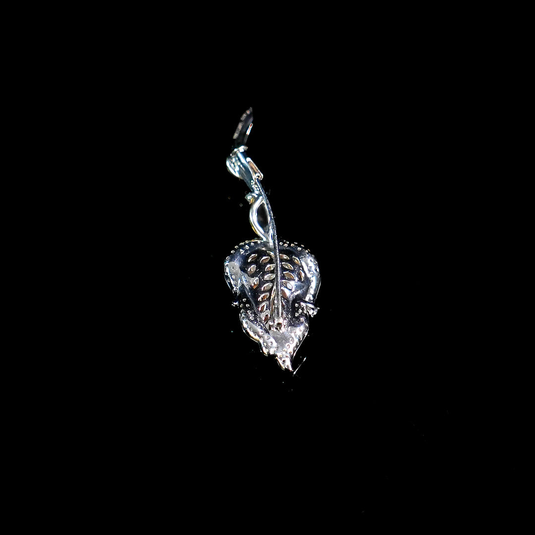 Silver-toned leaf brooch with engraved texture and jade-like green center.