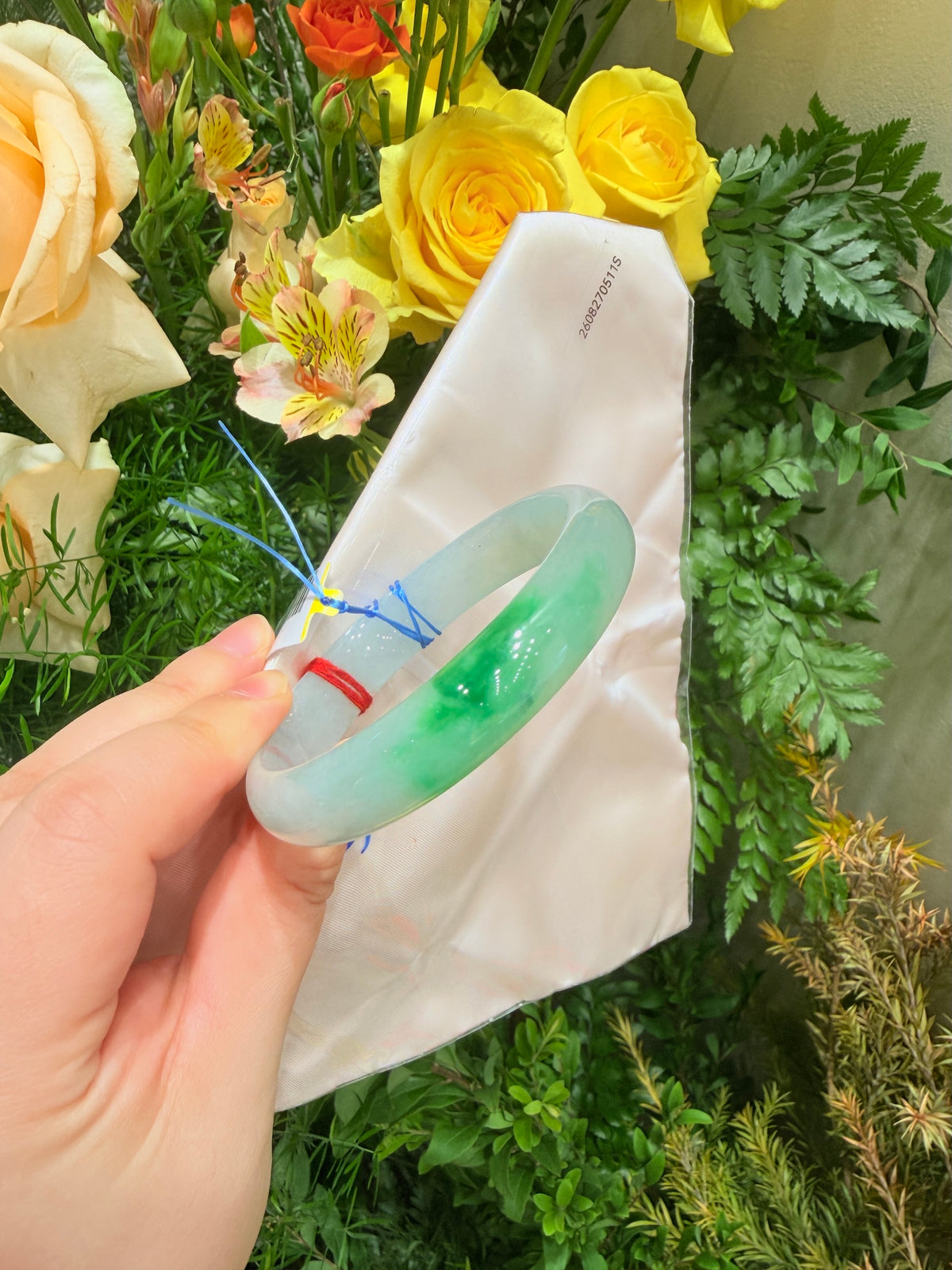 Translucent green jadeite bangle with glossy finish, held in hand for side view.