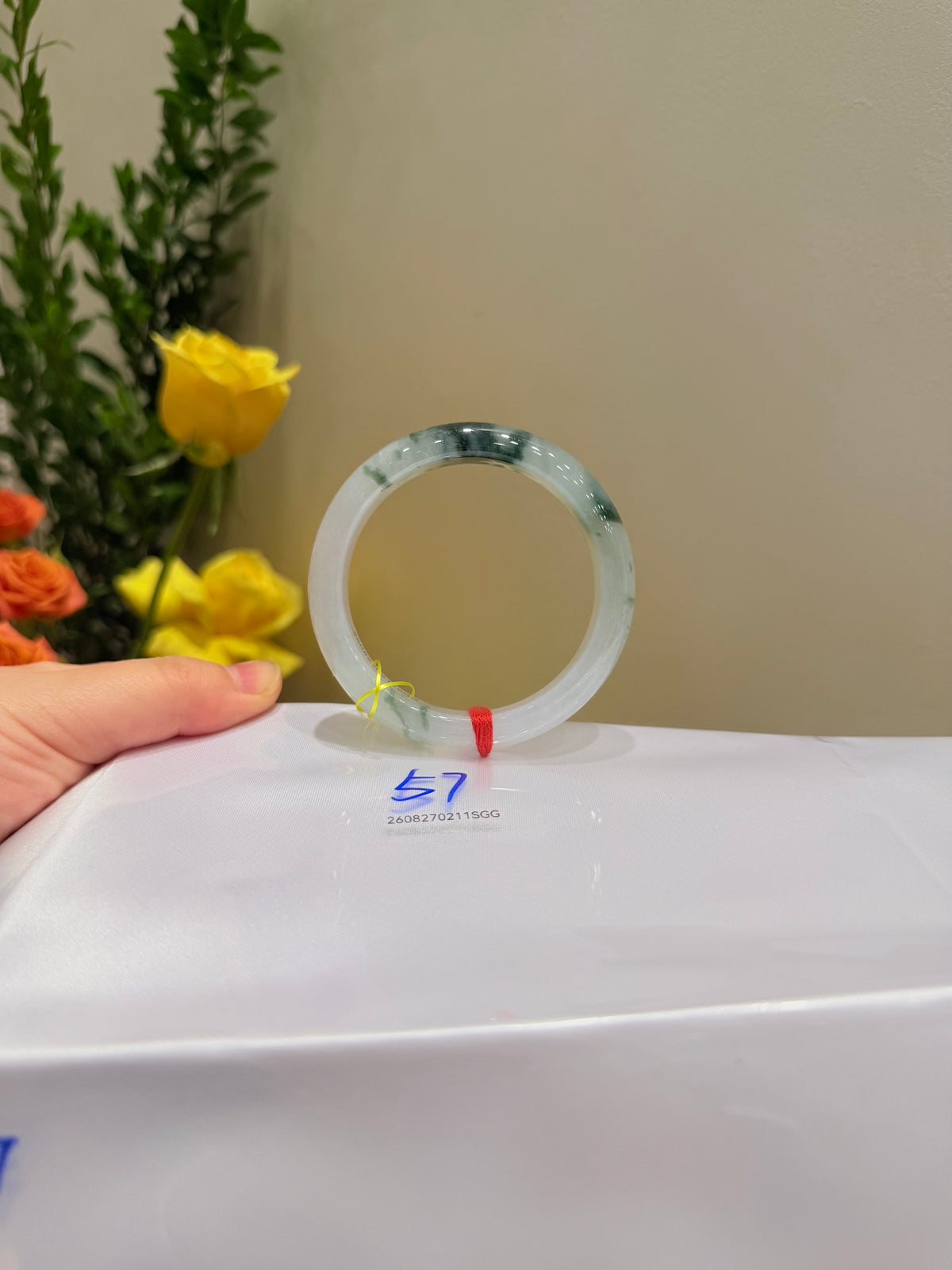 Jadeite bangle display, circular translucent light jade green cuff with polished surface