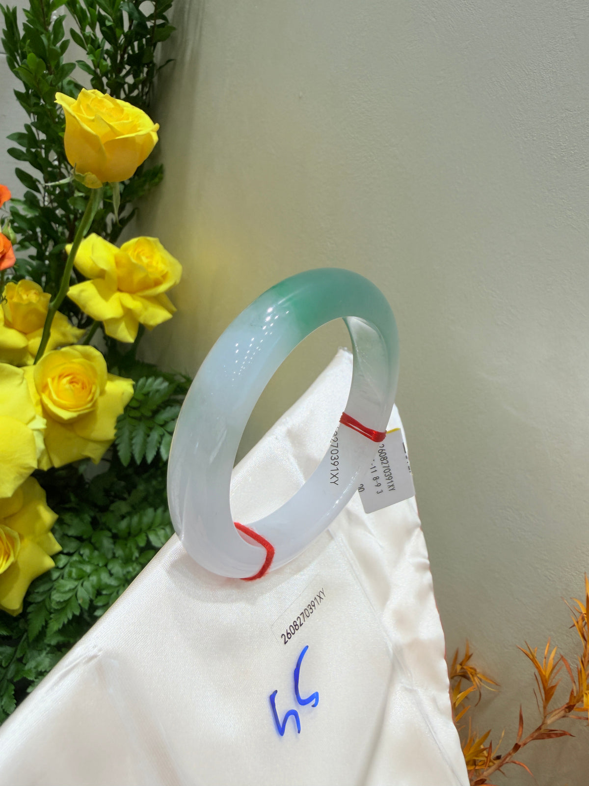 Light blue translucent bangle angled view on white wrap, brand tag attached