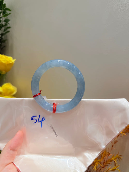 Smoky blue-gray round jadeite bangle on white pouch, partial hand
