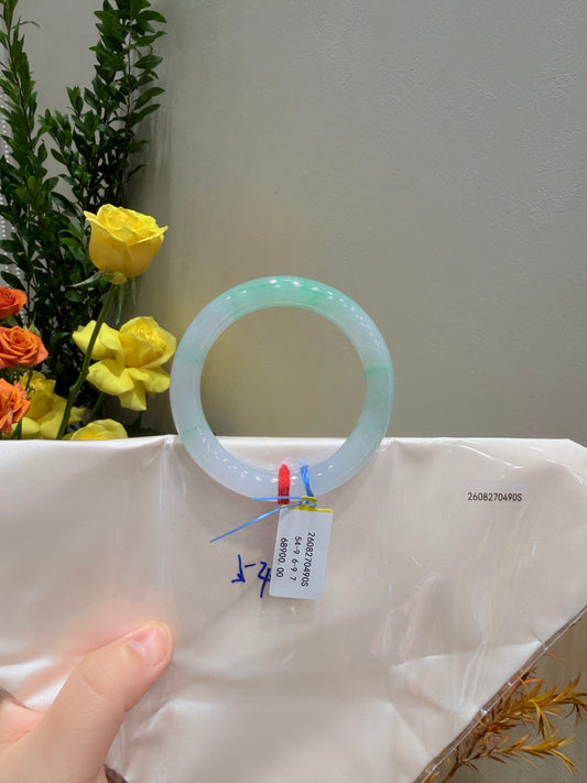 Pale mint-green jadeite bangle on a bag, ring centered with product label