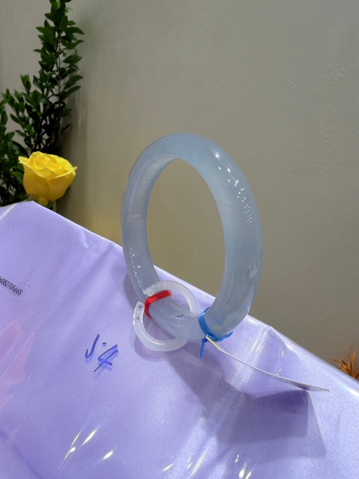Light blue translucent bangle bracelet on display with small red tie detail.